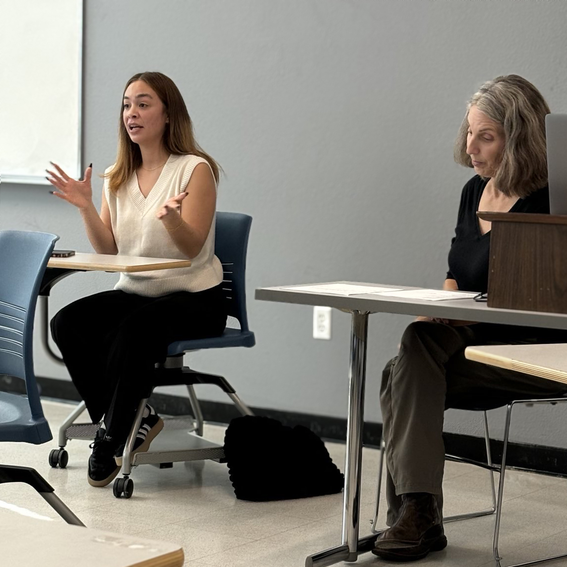 Humanities MA alum Caitilin Damacion and Cristina Ruotolo mid discussion in a classroom