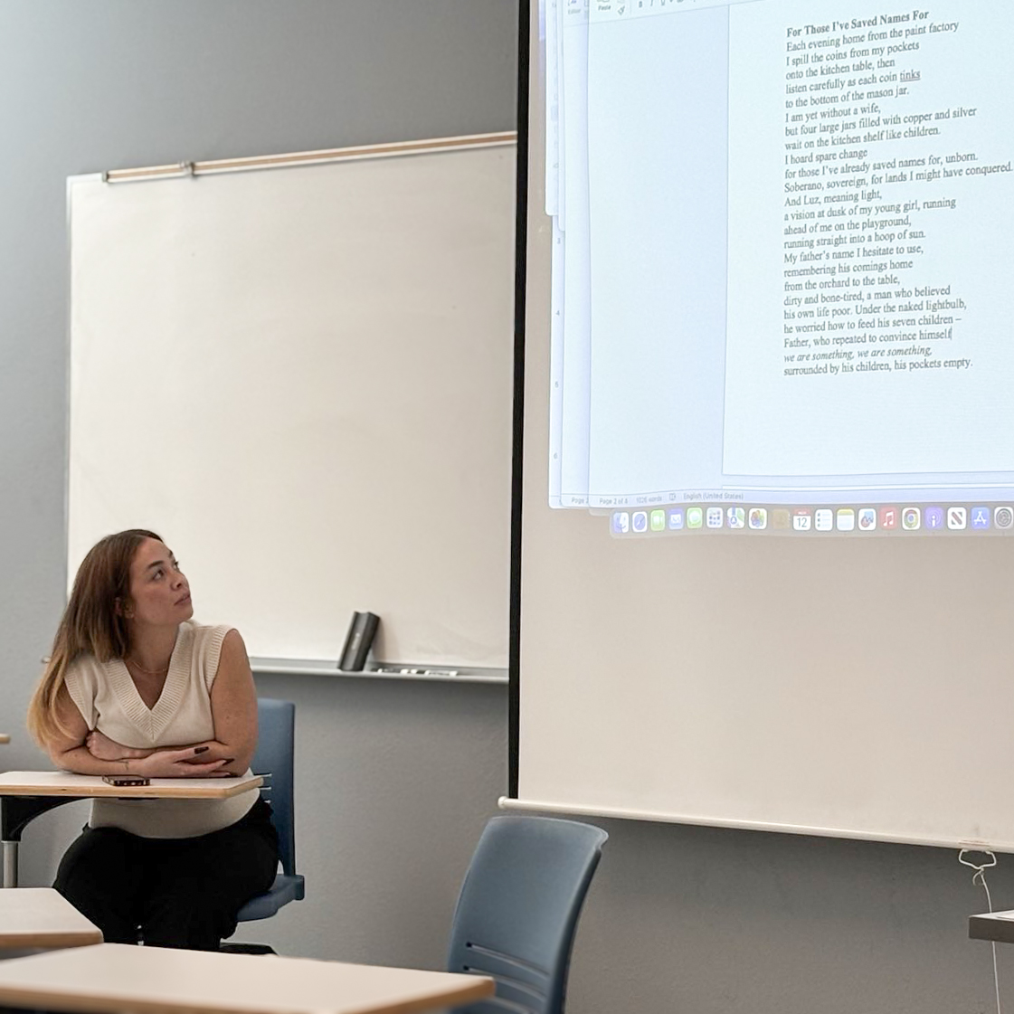 Humanities MA alum Caitilin Damacion looking up at the projector screen displaying poetry in a classroom