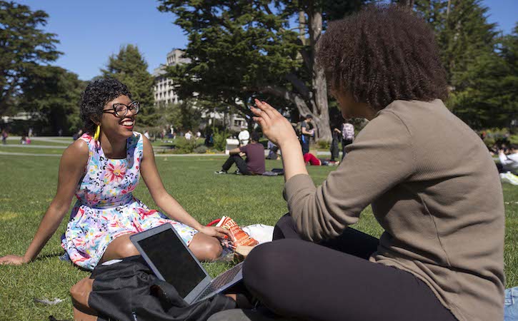 Two students sitting outside talking and laughing